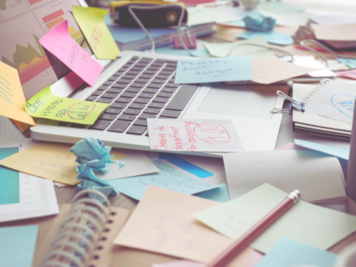a laptop with post it note reminders of dates and times, its a chaotic mess
